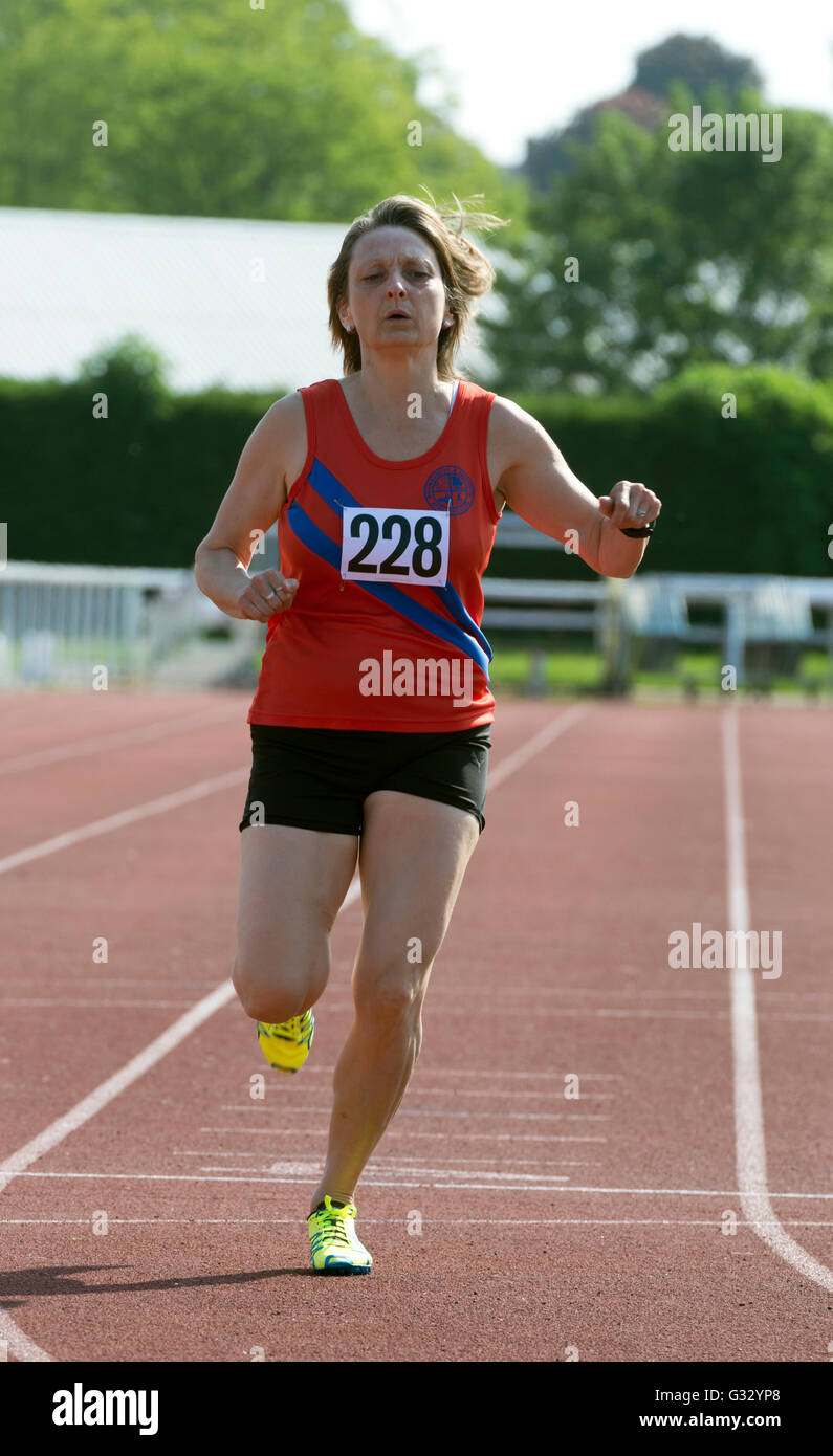 Masters athletics UK. Athlete finishing in women`s 400m race. Stock Photo